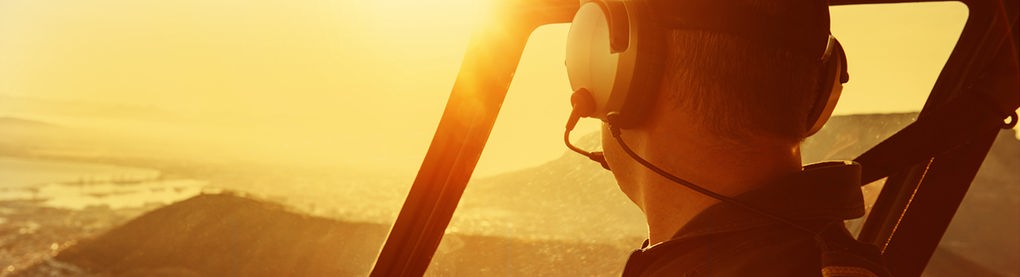 Pilot im Hubschrauber fliegt in den Sonnenaufgang