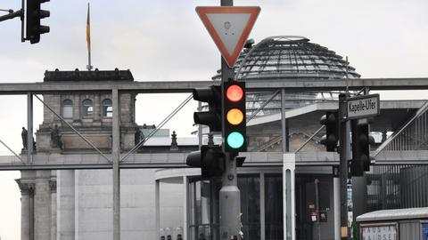 Eine Ampel im Regierungsviertel vor der Reichstagskuppel. 