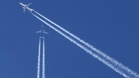 Kondensstreifen zweier Flugzeuge am blauen Himmel