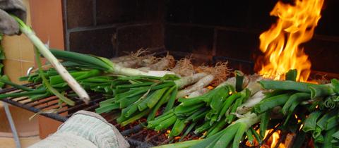 Die Calçots ist eine Art Frühlingszwiebel bzw. Lauchzwiebel. Sie wird gegrillt, bis ihre äußere Schichte schwarz ist und wird traditionell auf halbrunden Dachziegeln serviert.