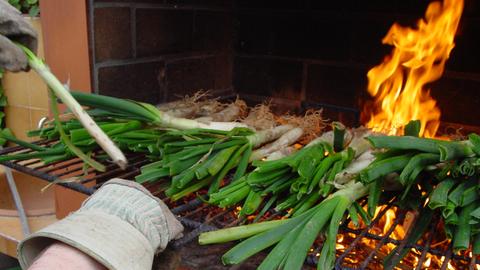 Die Calçots ist eine Art Frühlingszwiebel bzw. Lauchzwiebel. Sie wird gegrillt, bis ihre äußere Schichte schwarz ist und wird traditionell auf halbrunden Dachziegeln serviert.