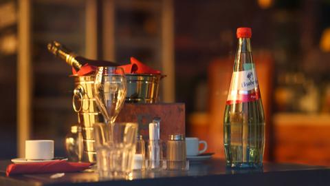 Auf einem gedeckten Tisch stehen eine Wasserflasche und eine Sektflasche 