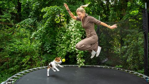 Tamara Gräfin von Nayhauß spielt mit ihrem Welpen Cookie auf einem Trampolin.