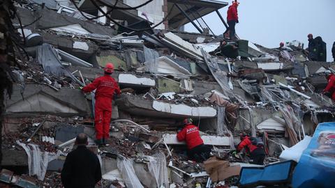 Rettungskräfte suchen nach Überlebenden auf den Trümmern eines Gebäudes. 