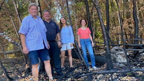 Mitglieder des Ortsvereins Heusenstamm/Obertshausen der Schutzgemeinschaft Deutscher Wald begutachten eine verkohlte ehemalige Brandstelle im Wald. 