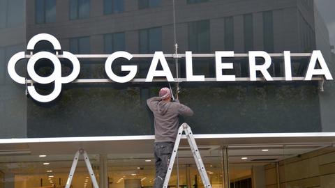 Ein Arbeiter montiert das neue Firmenschild und Logo Galeria an die Fassade des Kaufhaus auf der Einkaufsstraße Zeil. 