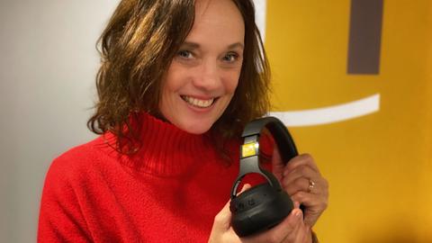 hr1-Moderatorin Susanne Schwarzenberger präsentiert den Kopfhörer, den es bei der Aktion hr1-Teamplayer für die Hörer*innen zu gewinnen gibt.