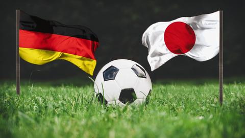 Deutsche und japanische Flagge mit Fußball in der Mitte